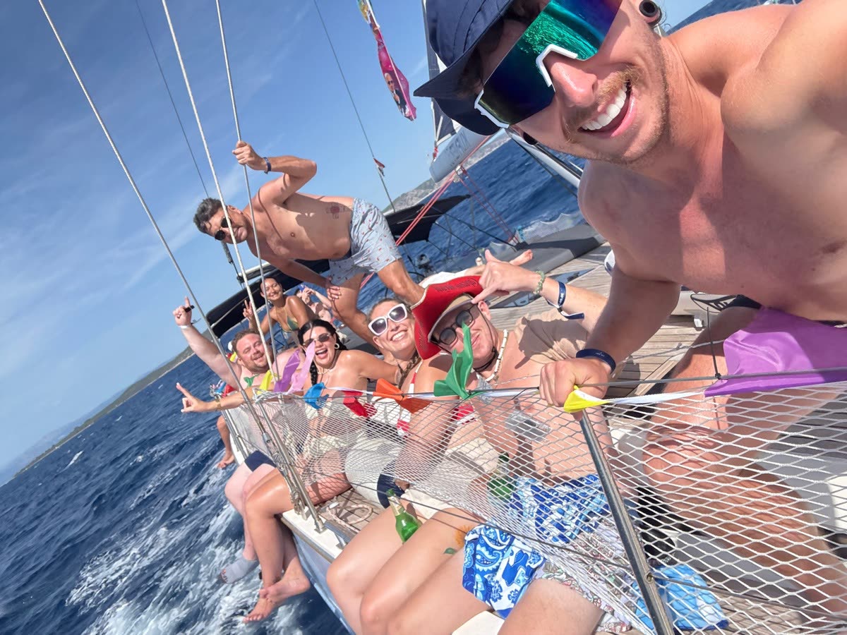 A close selfie on the bow netting of a yacht with the rest of the group stretched out behind