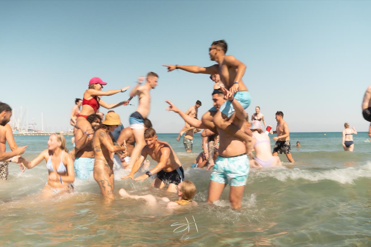 People messing about in the shallows, one sitting on another's shoulders