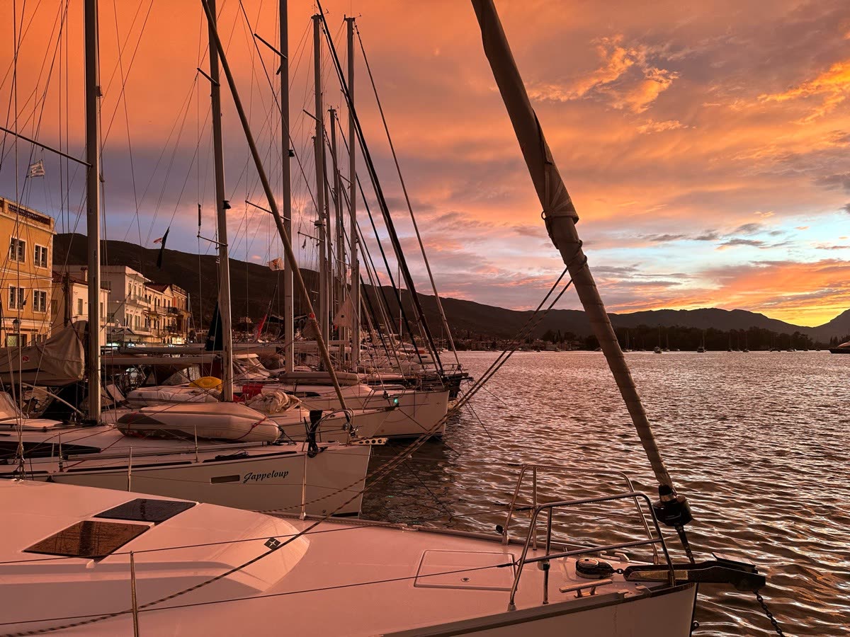 Yachts moored in a harbour under an orange sunset sky