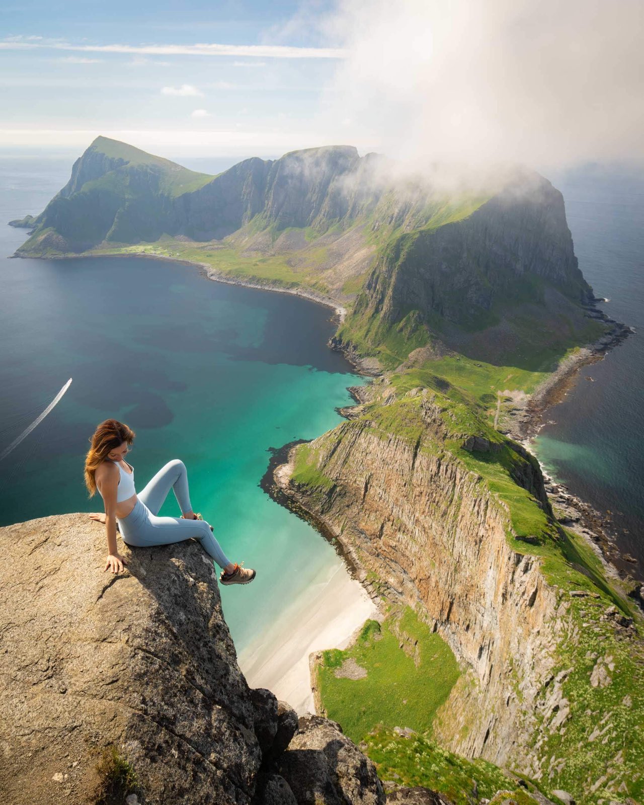 Sitting on the cliff edge above a turquoise bay on Værøy