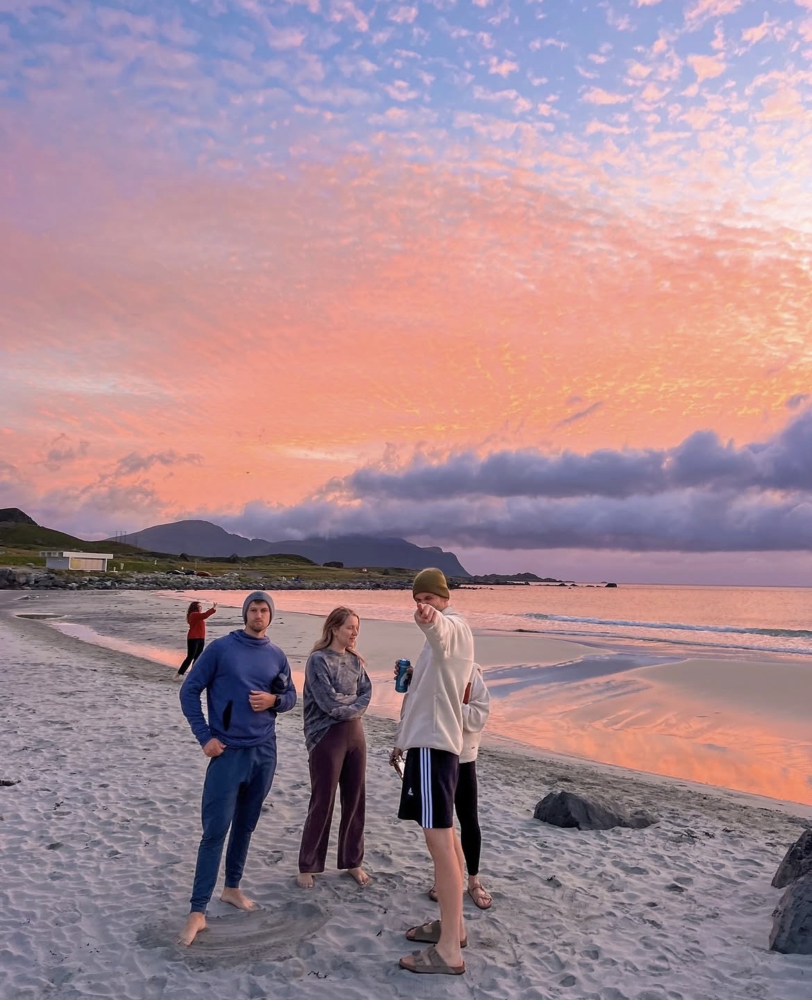 Four of the group on the sand under a pink and orange sky