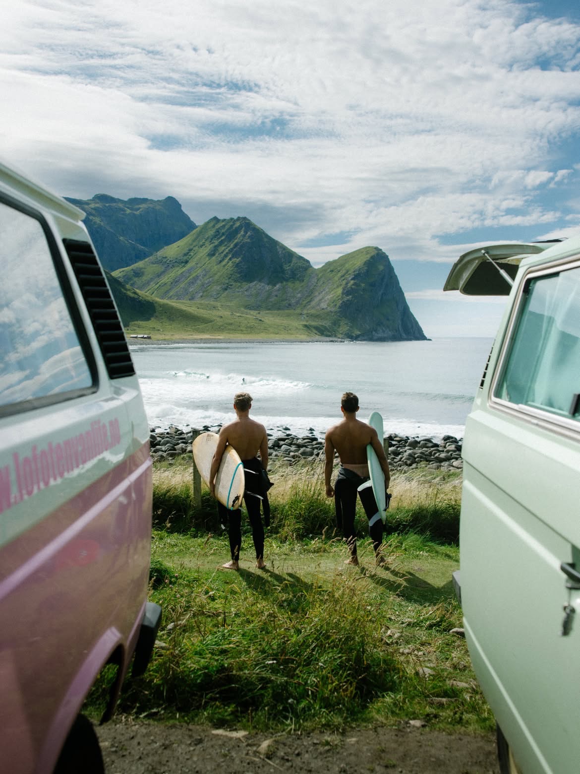 Two campers framing a pair of surfers walking down to the water