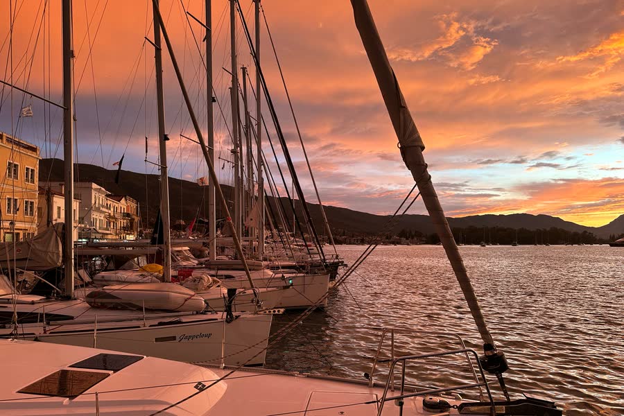 Yachts moored side by side in the marina under an orange sunset