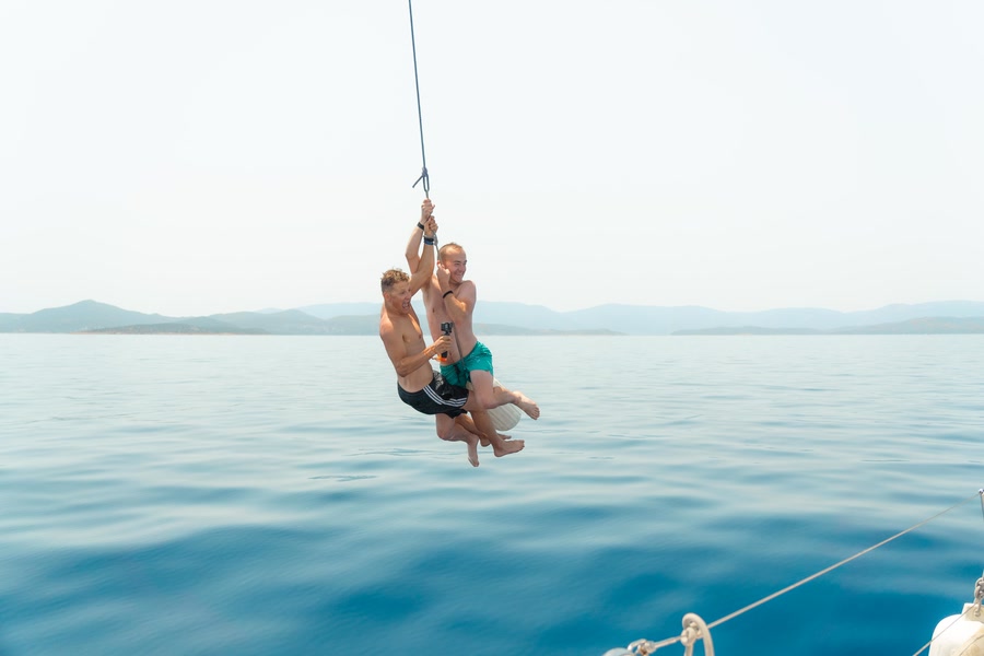 Two people on a rope swing out over flat water