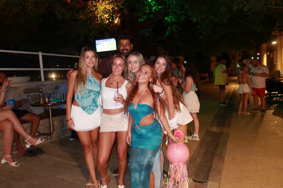 A group dressed up on a tree lined street at night